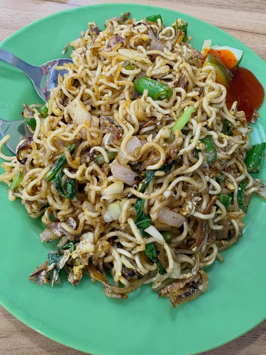 Maggi goreng with ikan bilis, egg and greens on a mint-green plate at Zaiqa’s Cafe