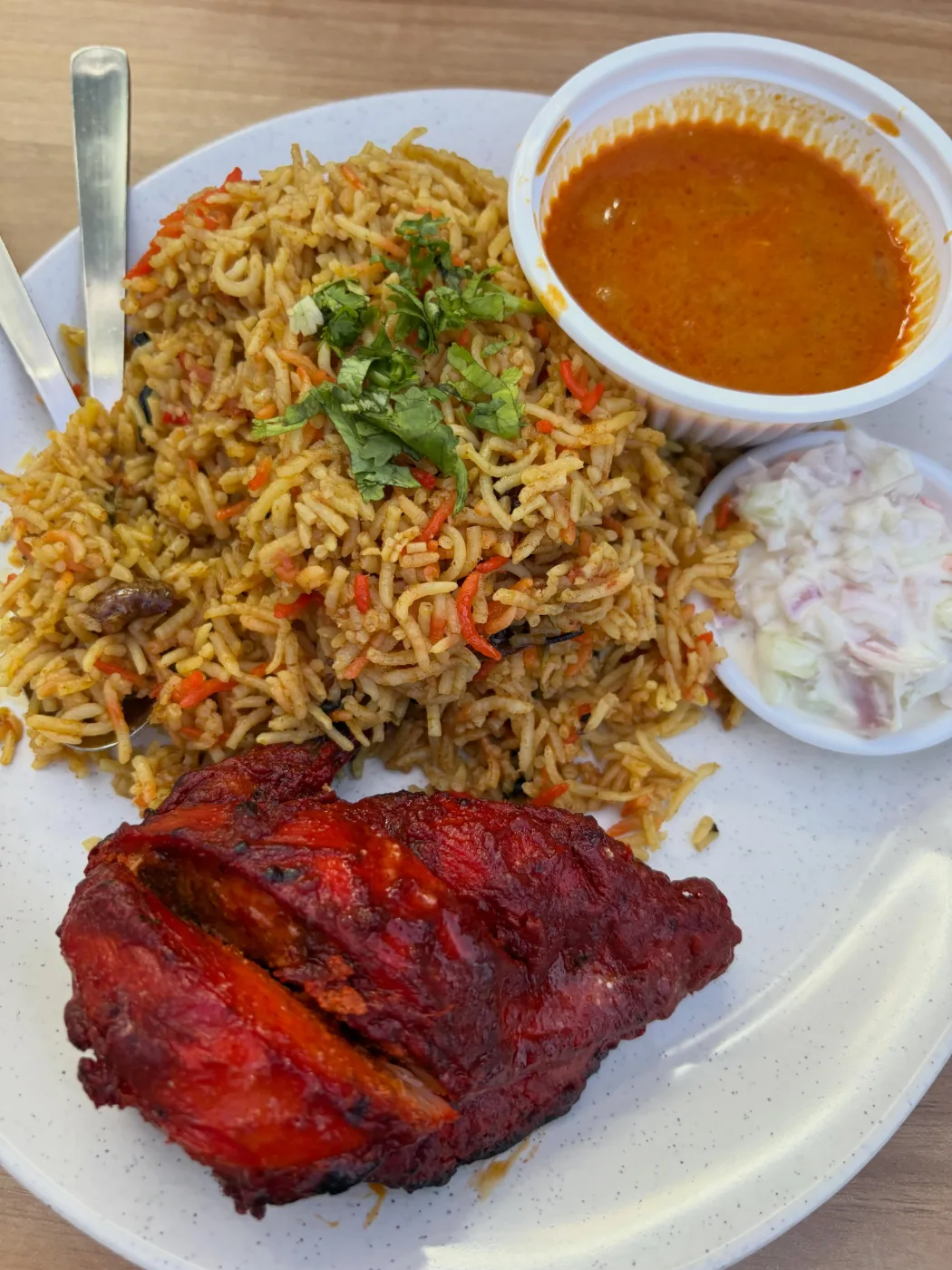 Charred red tandoori chicken with briyani rice, curry and raita at Zaiqa’s Cafe