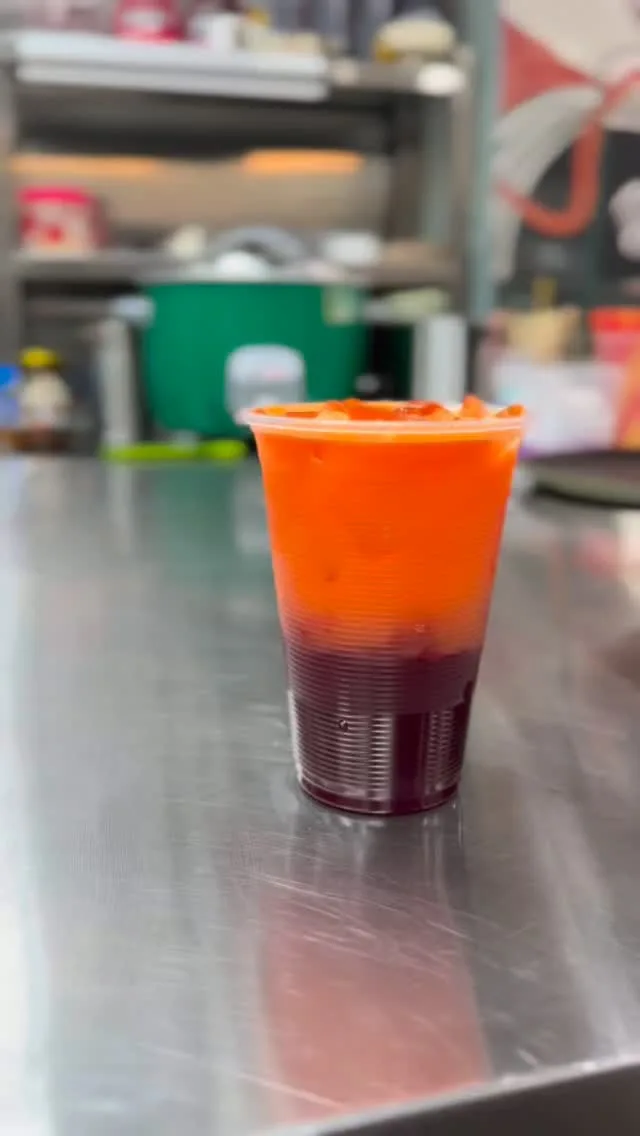 Tall layered iced drink in a takeaway cup on the drinks counter at Zaiqa’s Cafe